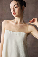 Woman wearing Vogsion Architectural Column Gown in sand against a neutral background