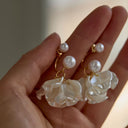 Vogsion Sculptural Petal & Lustrous Drop Earrings held in a hand against a neutral background