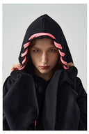 Person wearing a black hoodie with pink accents on a gray background