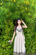 Woman in Vogsion "Lucienne" Ethereal Tulle & Contrast Lace-Inset Midi Dress standing in front of green foliage with yellow flowers