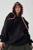 Person wearing a black hoodie with pink accents on a plain background