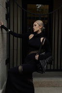 Vogsion x Nophora Obsidian Ecliptic Avant-Garde Maxi Gown worn by a customer, featuring black turtleneck, shoulder cut-outs, and diagonal sheer mesh panels.