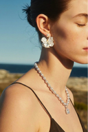 Woman wearing The Vogsion "Blush Radiance" Pearl & Crystal Pendant Necklace with a scenic background