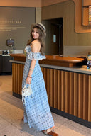 Woman in a blue polka dot dress standing in front of a coffee shop counter.