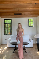 Woman in a Vogsion Strapless Twist Knot Satin Draped Maxi Dress standing in a modern living room with white sofa and wooden ceiling.