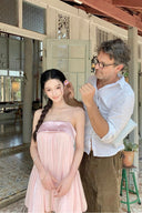 Woman in a Vogsion Odette Pearl-Trim Bubble Mini being styled by a man in a white shirt in a room with wooden beams and a plant.