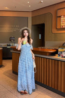 Woman in a Vogsion L’Avenir Polka-Dot Lace Ruffle Maxi Dress in Powder Blue standing in a Starbucks Reserve Bar.