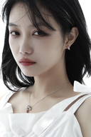 Woman wearing a white top and silver necklace with a clear pendant on a white background