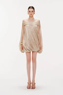 Vogsion Neutral Draped Glossy Mini Dress - A high-shine champagne off-the-shoulder dress with sculptural draping and cape sleeves worn by a Vogsion customer