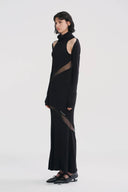 Vogsion x Nophora Obsidian Ecliptic Avant-Garde Maxi Gown worn by a customer, featuring black turtleneck, shoulder cut-outs, and diagonal sheer mesh panels.