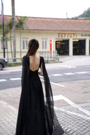 Vogsion Open Back Ribbon Maxi Dress – Elegant black pleated chiffon halter neck evening gown with dramatic sheer ribbon cape sleeves, open back cutouts, and flowing maxi skirt, worn by real Vogsion customer (not professional model) in luxury setting with global fast shipping