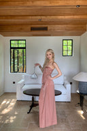 Woman in a Vogsion Strapless Twist Knot Satin Draped Maxi Dress standing in a modern living room with wooden ceiling and white walls.