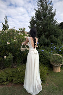 Woman in a Vogsion Amber Light Lace Spliced Open Back Tie Strap Maxi Dress standing in a garden with greenery and flowers.