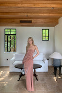 Woman in a Vogsion Strapless Twist Knot Satin Draped Maxi Dress standing in a modern living room with white furniture and wooden ceiling.