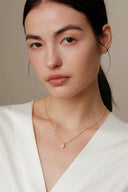     Vogsion Minuit Éclat dainty oval moissanite pendant necklace on gold-tone chain styled on natural customer-style model.