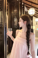 Woman in a Vogsion Odette Pearl-Trim Bubble Mini holding a glass in an elegant interior setting