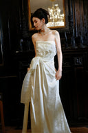 Woman in a Vogsion 2026 3D Blooming Rose Strapless Ruched Pleated Wedding Dress standing in a room with dark wood furniture and a chandelier.
