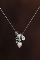 Necklace with strawberry-shaped pendant and other charms on a dark background