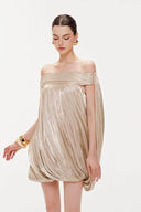 Vogsion Neutral Draped Glossy Mini Dress - A high-shine champagne off-the-shoulder dress with sculptural draping and cape sleeves worn by a Vogsion customer