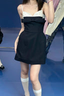 Person wearing Vogsion Antoinette Structured Bow Tailored Mini Dress with white lace top on a blue floor.