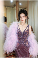 Woman in a Vogsion "Midnight Butterfly" Iridescent Sequin Backless Evening Gown with a feathered shrug in front of a mirror.