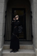 Vogsion x Nophora Obsidian Ecliptic Avant-Garde Maxi Gown worn by a customer, featuring black turtleneck, shoulder cut-outs, and diagonal sheer mesh panels.