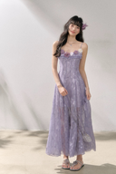 Woman wearing a long purple floral dress against a plain background