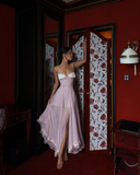 Blush pink petite wedding guest ruffle dress with ruched bodice and white lace bust detail indoor