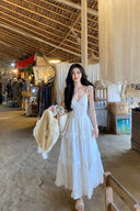 Model wearing vogsion ethereal white camellia dress walking in a garden, flowing tiered skirt for summer aesthetic.