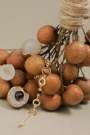 Gold bracelet with gemstone charm on a background of longan fruits