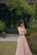 Vogsion soft pink corset maxi dress thoughtful pose with lace bodice outdoors