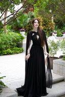 Vogsion Open Back Ribbon Maxi Dress – Elegant black pleated chiffon halter neck evening gown with dramatic sheer ribbon cape sleeves, open back cutouts, and flowing maxi skirt, worn by real Vogsion customer (not professional model) in luxury setting with global fast shipping