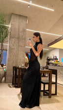 Woman in a Vogsion Noir Eclipse Sheer Halter Maxi Dress taking a selfie in a modern interior setting.