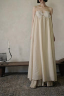 Vogsion Santorini Scalloped Lace Maxi Dress in cream, featuring delicate floral lace bust detailing and a fluid, floor-length silhouette.
