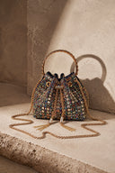 Colorful crystal embellished VS Beaded Bucket Bag with gold top handle on textured stone background