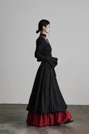 Woman wearing a black coat and red skirt against a plain background