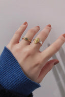 Hand wearing Vogsion Le Brunch Croissant Shell Adjustable Ring with a blue sleeve against a neutral background