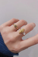 Hand wearing two gold rings, one is Vogsion Le Brunch Croissant Shell Adjustable Ring on a plain background