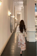 Woman walking down a stylishly decorated hallway with white walls and decorative elements.