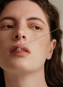 Close-up of a woman's face with a Vogsion Darcy Reverie Oval Gemstone Pendant Necklace over her mouth.