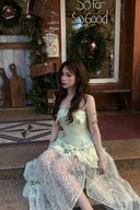 Woman in a Vogsion Pistachio Green Strapless Corset Ruffle Peplum Lace Prom Dress 2026 sitting on steps with a rustic background