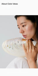 Person holding a large, decorative shell against a light background