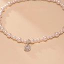The Vogsion "Blush Radiance" Pearl & Crystal Pendant Necklace on a beige background
