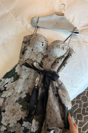 Vogsion Seraphina Floral Bustier Dress from the Kindred Spirit Spring 2026 collection, featuring a white and black botanical floral print, beaded straps, and a tie-waist, worn by a Vogsion customer in a historic European plaza
