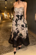 Vogsion Seraphina Floral Bustier Dress from the Kindred Spirit Spring 2026 collection, featuring a white and black botanical floral print, beaded straps, and a tie-waist, worn by a Vogsion customer in a historic European plaza