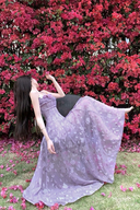Woman in a purple dress standing in front of a vibrant pink flowering bush