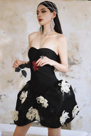 Woman wearing a Vogsion Midnight Bloom Architectural Mini Dress with floral embellishments against a marble background
