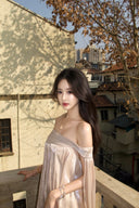 Vogsion Neutral Draped Glossy Mini Dress - A high-shine champagne off-the-shoulder dress with sculptural draping and cape sleeves worn by a Vogsion customer