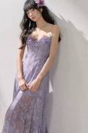 Woman in a purple dress with floral details against a white wall