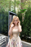 Person wearing a floral dress standing outdoors with greenery in the background